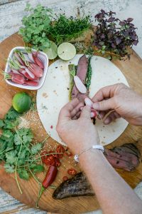 Wrap mit Hirschfilet, gruenem Spargel, Fruehlingszwiebeln, Radieschen und Sesam